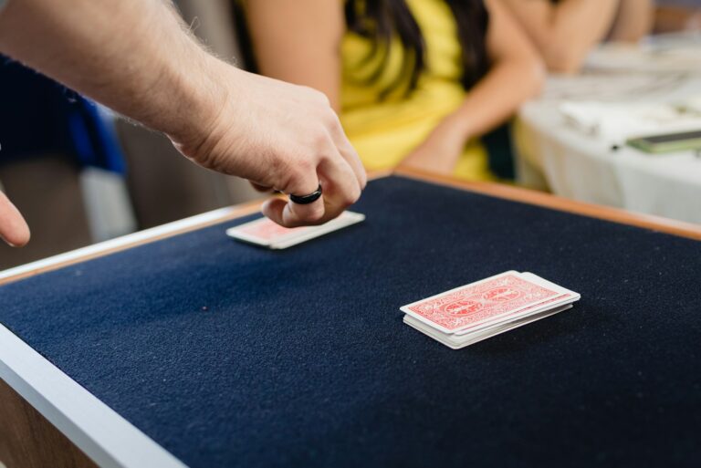 A magician performs a trick with cards face down on a mat.